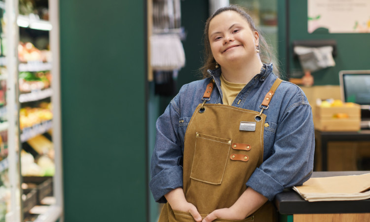 Eine junge weiße Mitarbeiterin mit Downsyndrom im Supermarkt