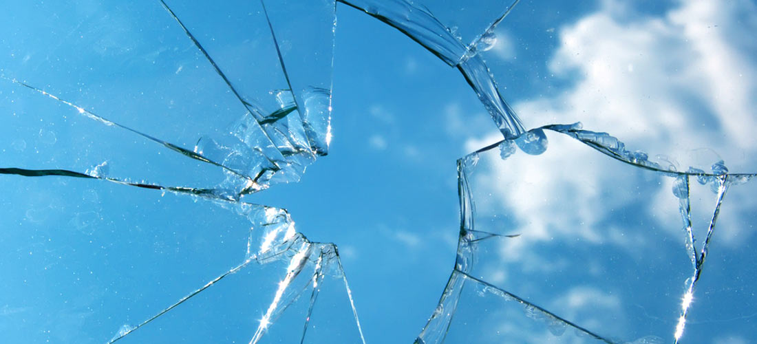 Eine zerbrochene Glas-Scheibe. Der Hintergrund ein blauer Himmel.